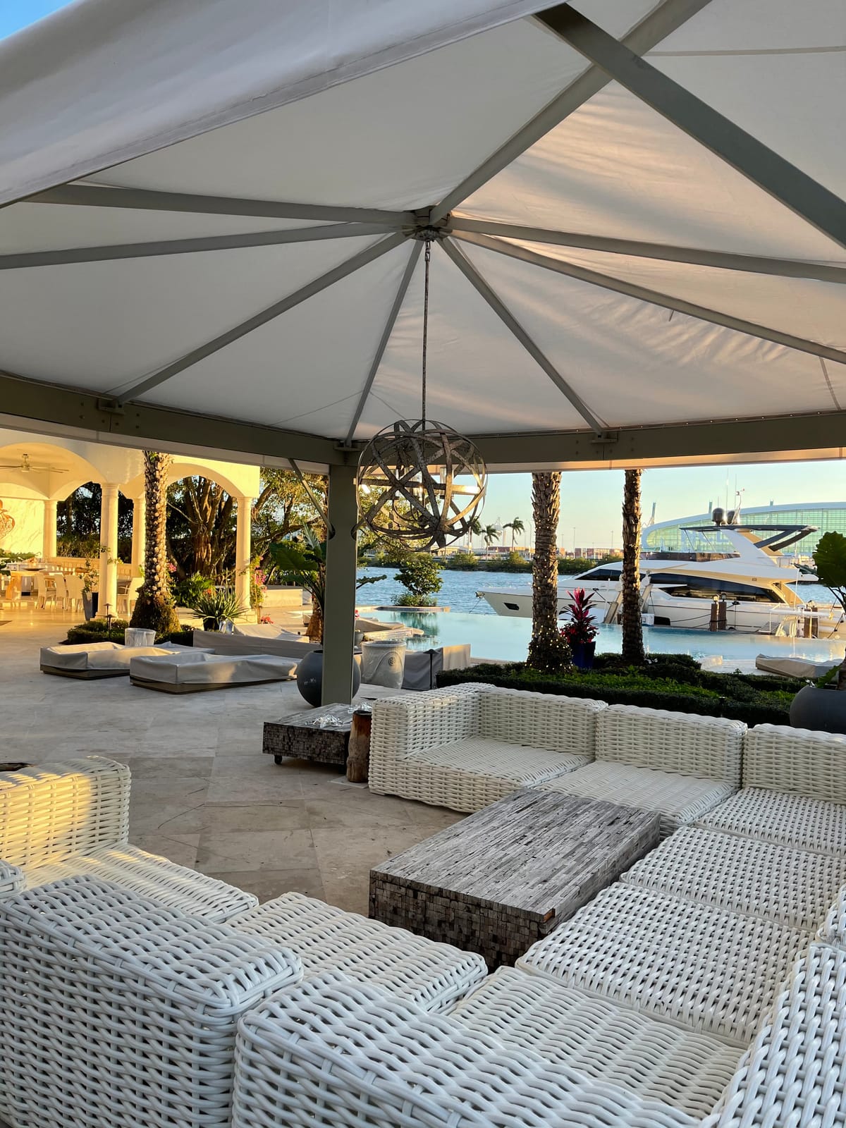 Custom waterfront cabana with a white canopy roof overlooking a pool and yacht, built by EAB Awnings in South Florida