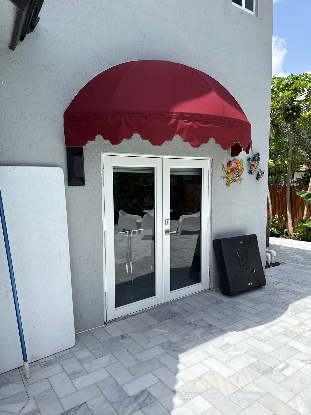 Rounded burgundy dome window awning with scalloped edge on a South Florida home